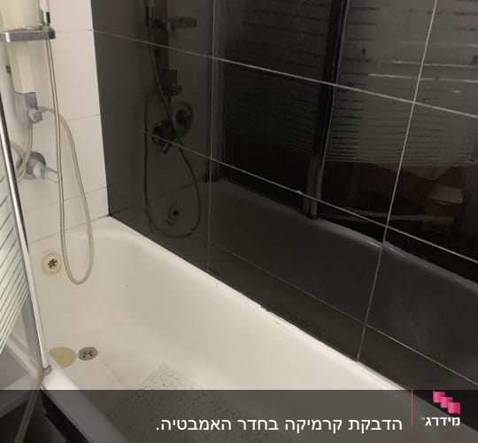 אמבטיה עם אריחים שחורים, ראש מקלחת וצינור מים